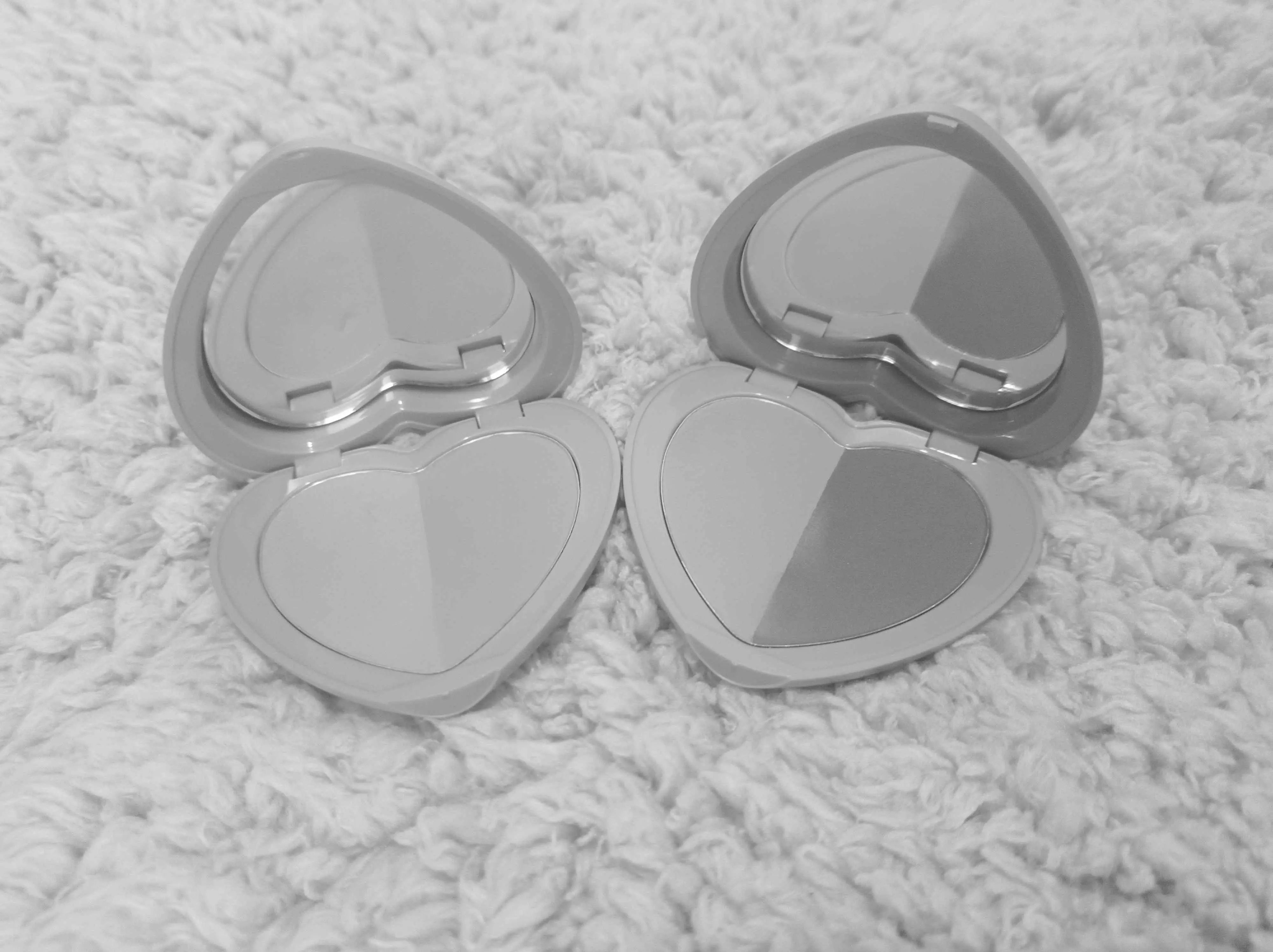 image: Pretty Betty and Sweet Missy compacts opened side by side with a black and white filter over the picture. Pretty Betty is a lighter pair compared to Sweet Missy in terms of value.